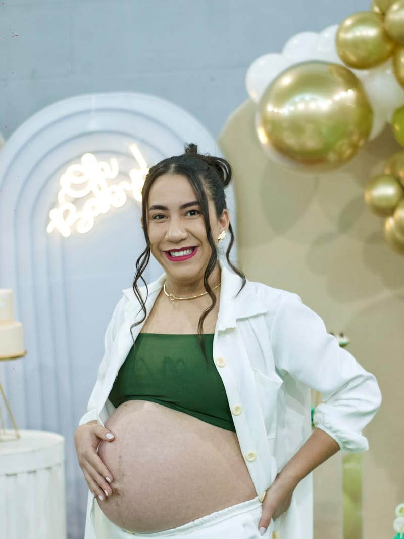 Gestante sorrindo com a mão na barriga no chá de bebê